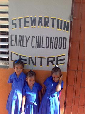 little girls stand under school sign