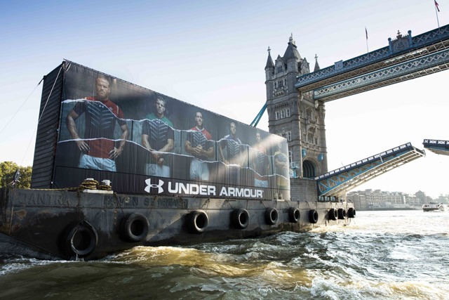 Under Armour shipping containers full of new Armour baselayer product pass under Tower Bridge on their way down the River Thames