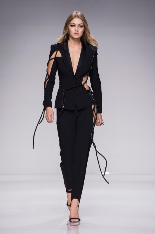 Gigi Hadid walks Atelier Versace’s spring 2016 show wearing a black pantsuit with cut-out details