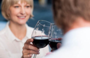 Attractive couple raises a glass of red wine in cafe.