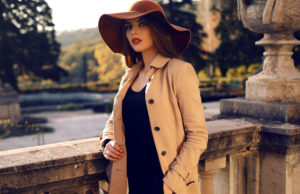 fashion outdoor photo of beautiful ladylike woman with dark straight hair wearing elegant coat and felt hat,posing in autumn park