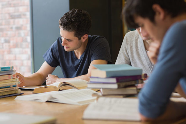 People sitting at the table while doing homework in college library