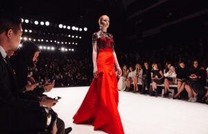 Best Fabrics to Use for Evening Gowns Women walking down the a catwalk in a red evening dress