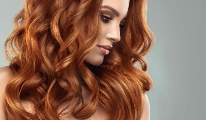 Beautiful model girl with long red curly hair .Red head . Care and beauty hair products
