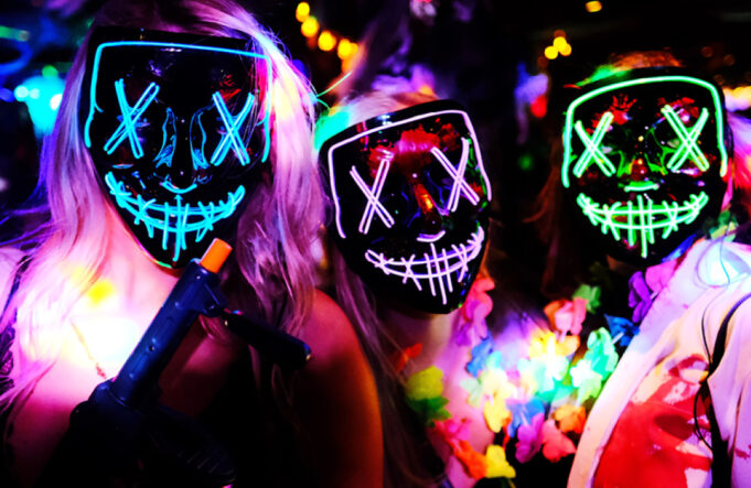 3 women wearing purge masks and fancy dress for Halloween