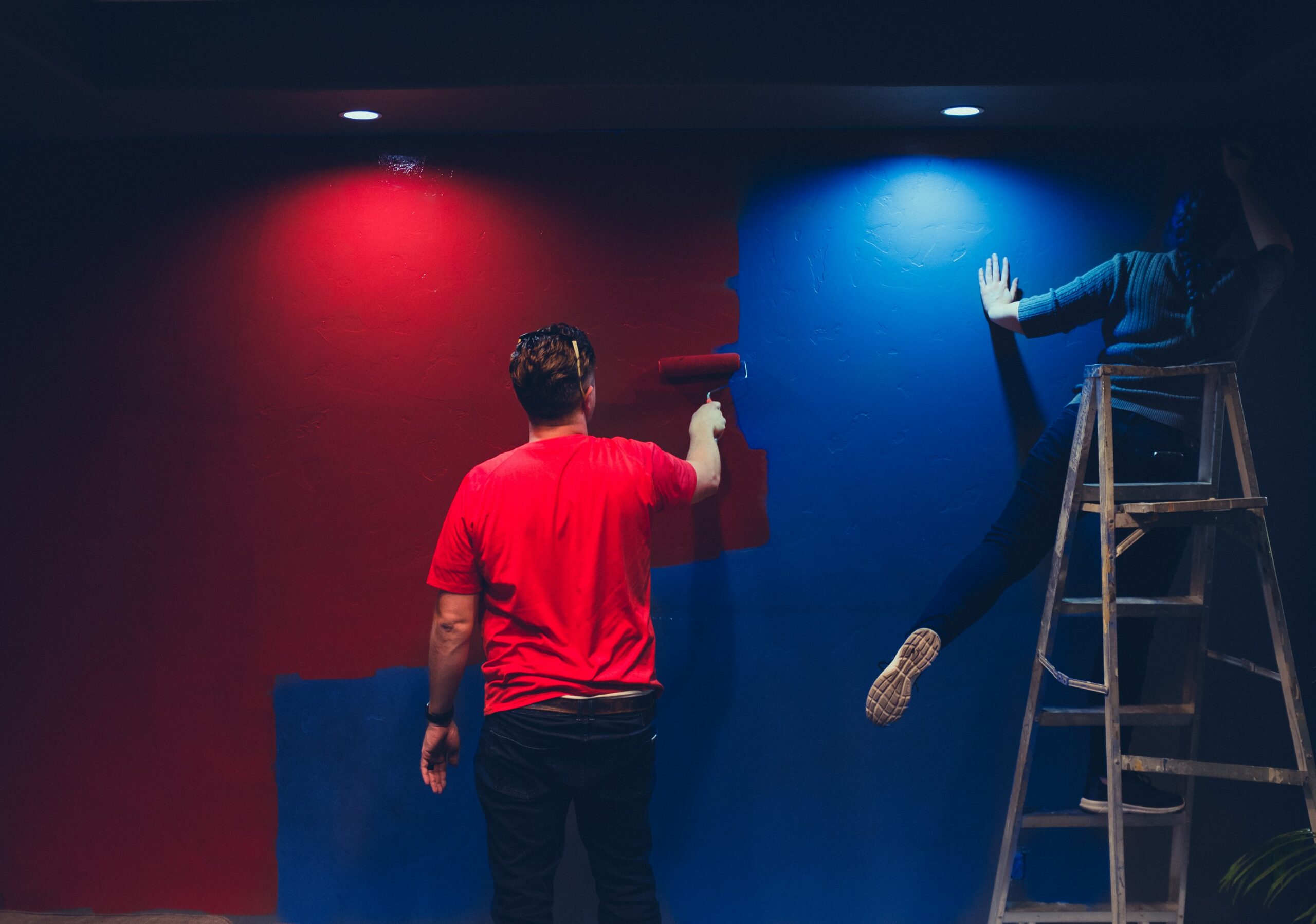 Photo of 2 men painting a wall in red and blue