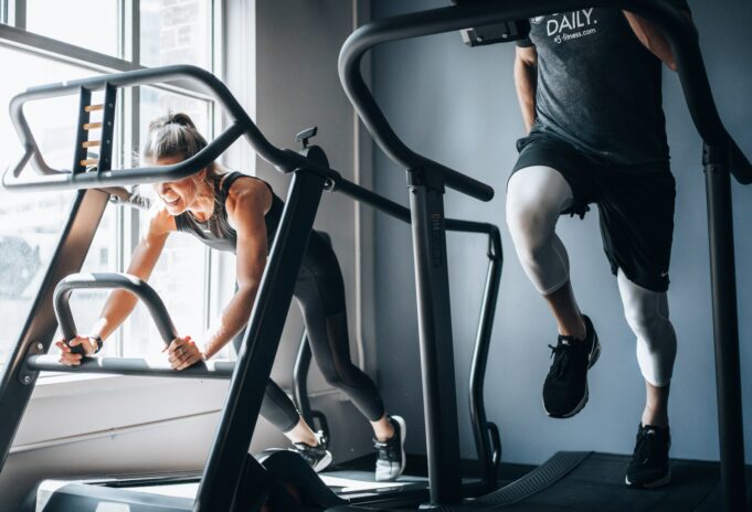 A woman a man using a running machine in a gym