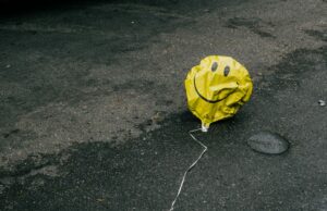 A photo of a deflated balloon with a smiley face on it
