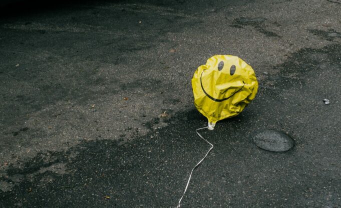 A photo of a deflated balloon with a smiley face on it