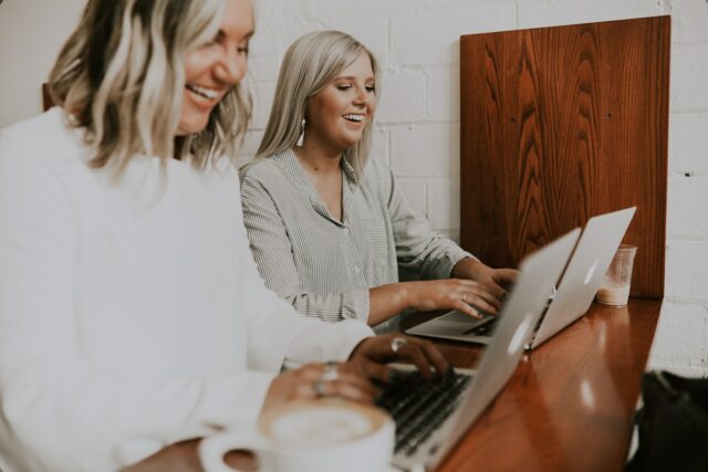 Two happy women using laptops
