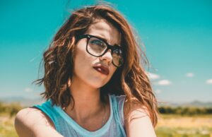 Unveiling Nature’s Secrets for Thicker Hair: Effective Techniques Revealed Woman with red hair, wearing black sunglasses sitting on a chair