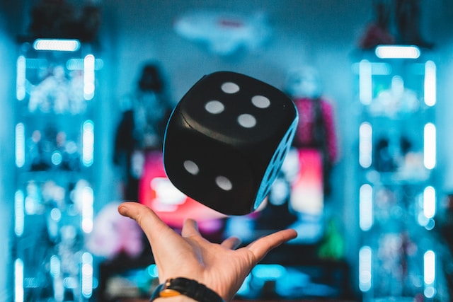 A person's left palm about to catch a black dice phoho