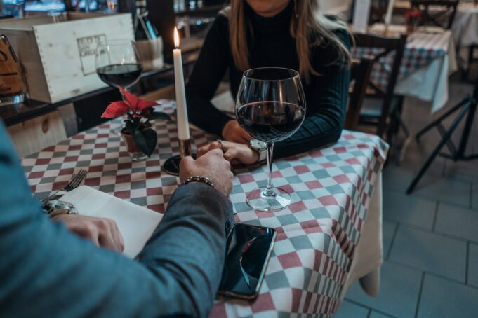 Man and women holding hands over a table with a glass of red wine