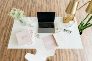 Grey and black laptop computer on white table with pink accessories
