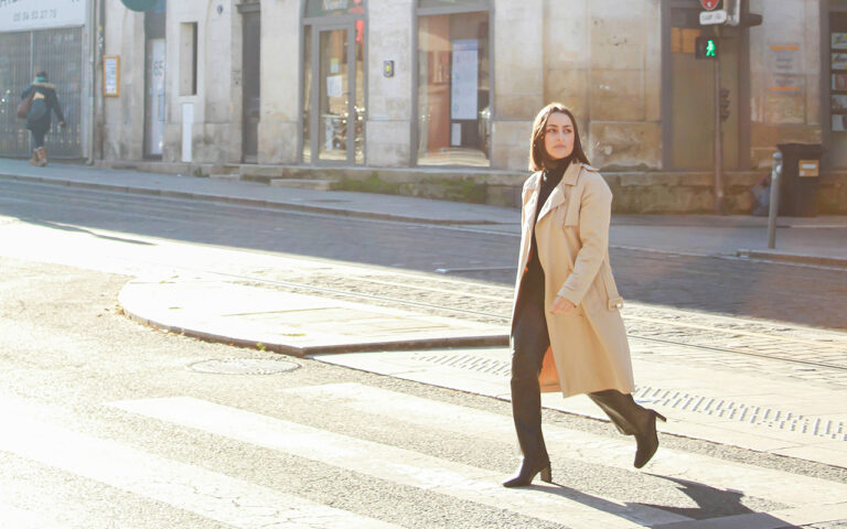 A woman walking across a street next to a tall building