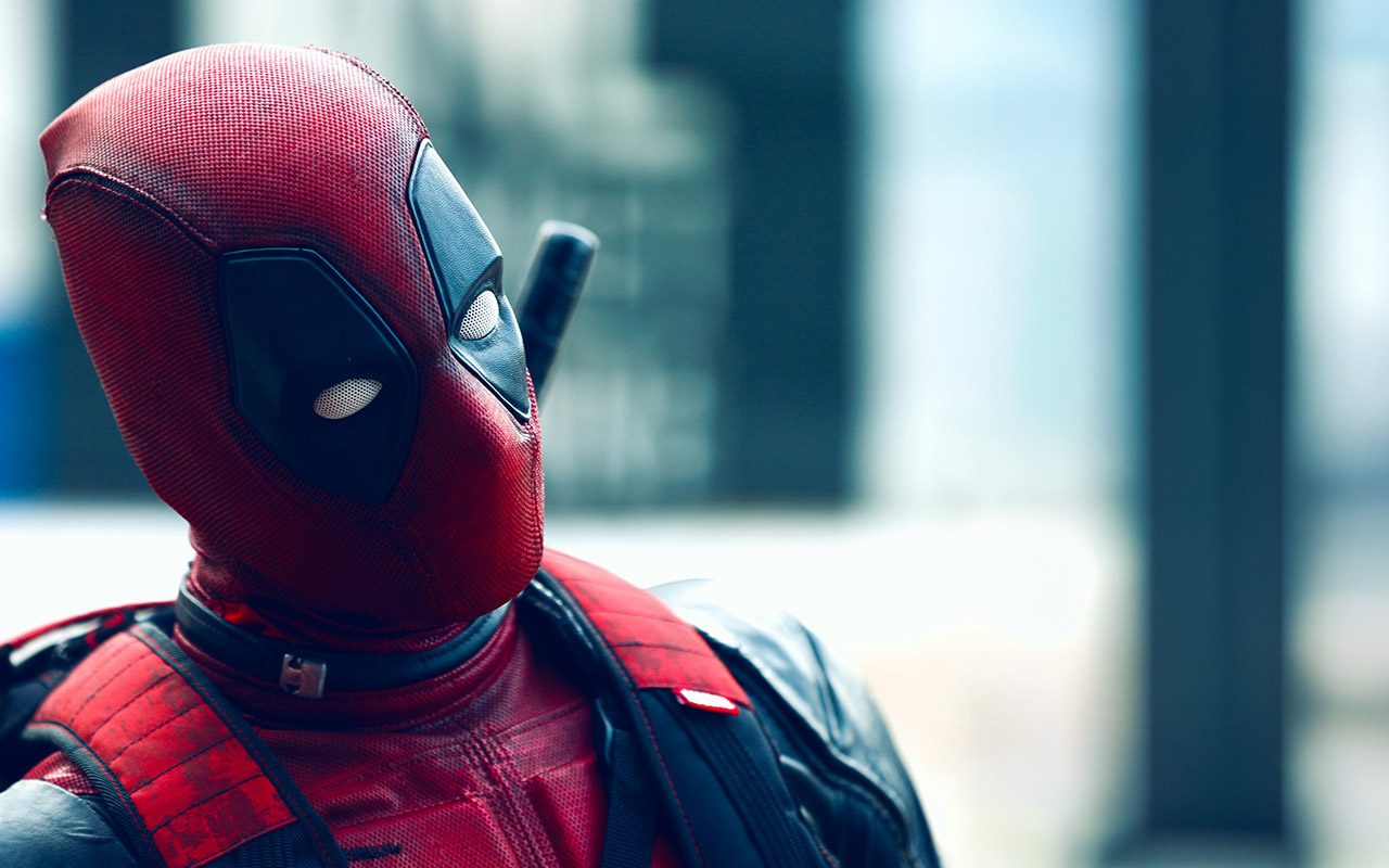 Close-up of a person wearing a red-and-black Deadpool costume and mask.