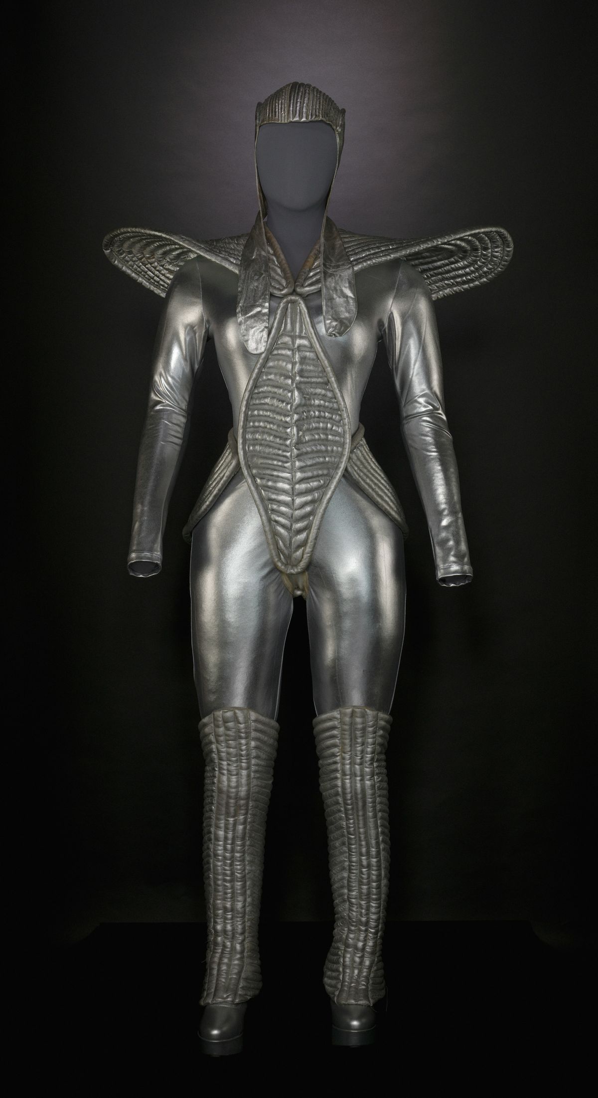 Silver costume on a mannequin, with sculpted shoulders, ribbed chest detailing and knee-high boots.
