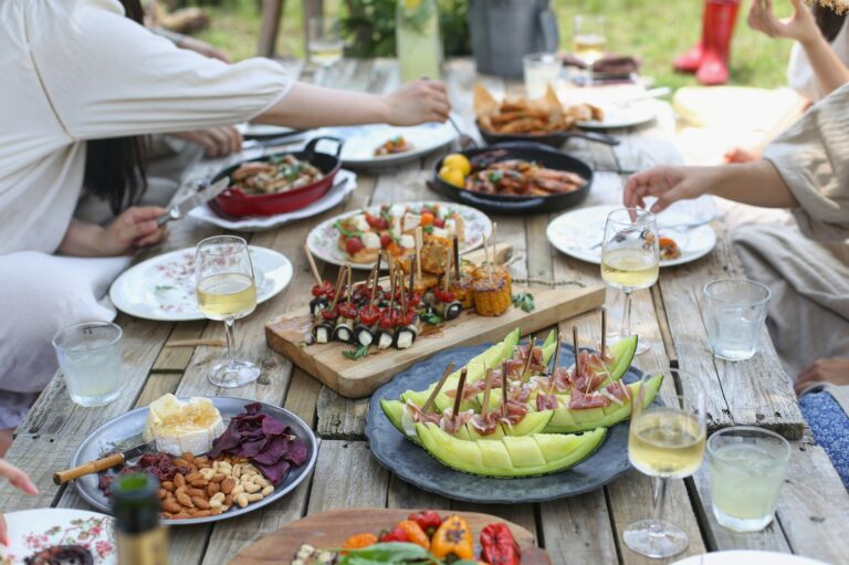 Group of people eating on a wooden table in a garden