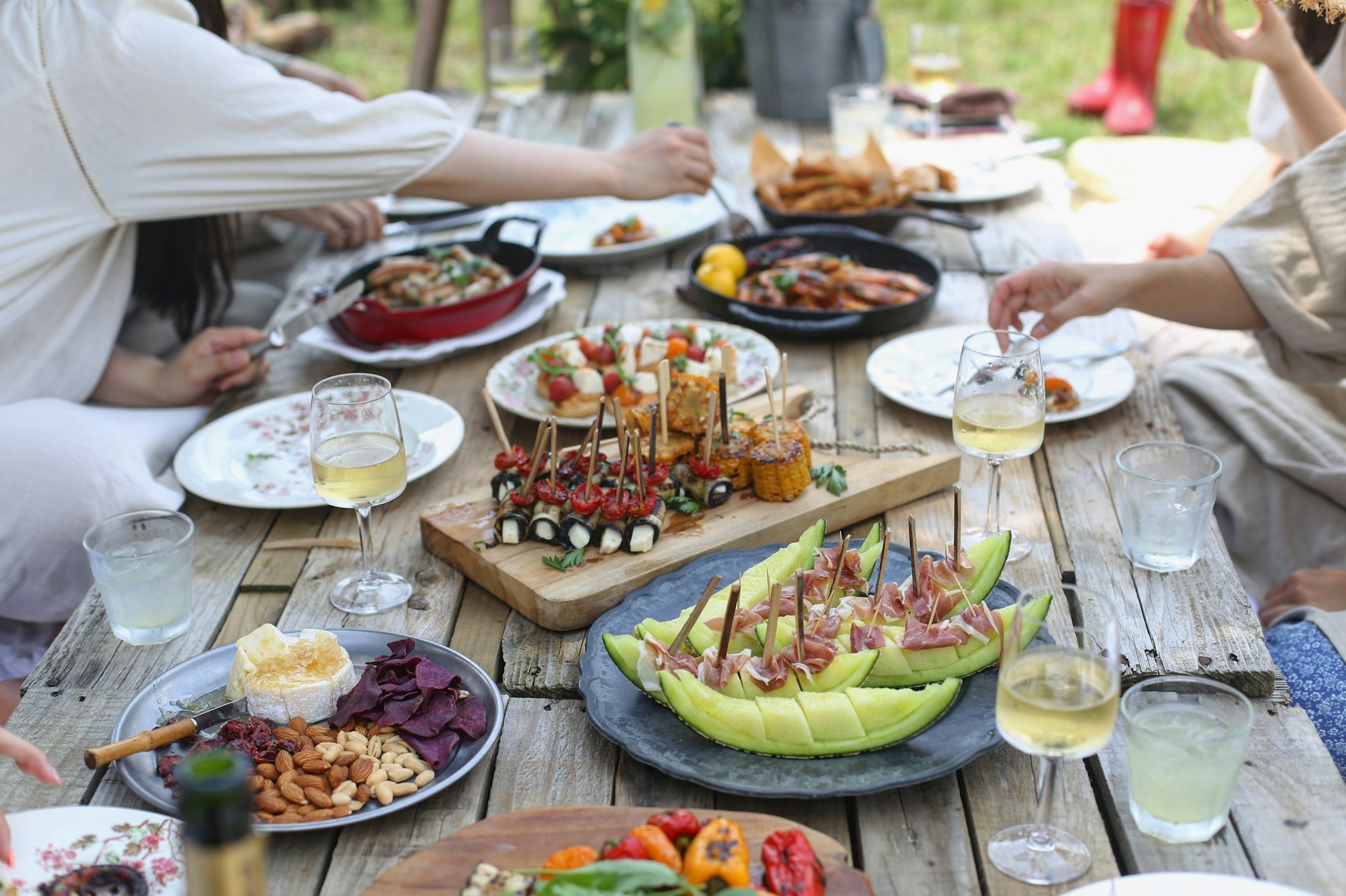 Group of people eating on a wooden table in a garden